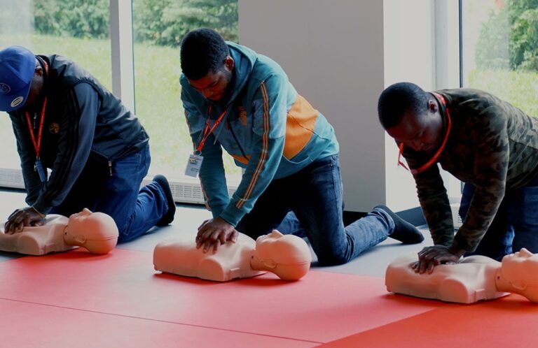 Trois stagiaires s'exercent au massage cardiaque sur des mannequins pendant une formation aux premiers secours